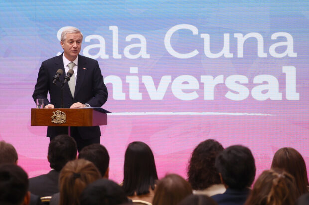 Presidente Kast habla desde un podio. Atrás de él una gigantografía azul y rosada con el texto "Sala Cuna Universal".