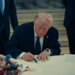 Mercados celebran acuerdo entre Estados Unidos e Irán, pero expertos ven un escenario marcado por la incertidumbre Donald Trump firmando un documento sobre una mesa con mantel blanco.