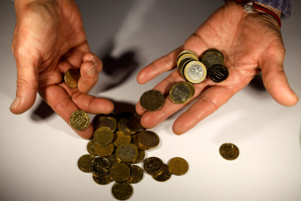 Manos de un adulto mayor sosteniendo monedas.