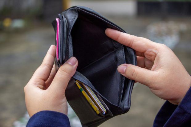 Manos sosteniendo una billetera abierta y vacía en su interior.