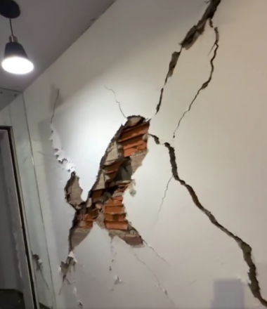 Gran grieta deja ver ladrillos de una pared blanca.