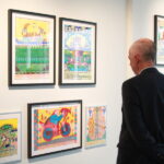 Artista chileno expone por primera vez en forma individual en uno de los principales museos de Art Brut del mundo Vista trasera de un hombre observando una exposición de cuadros de arte.