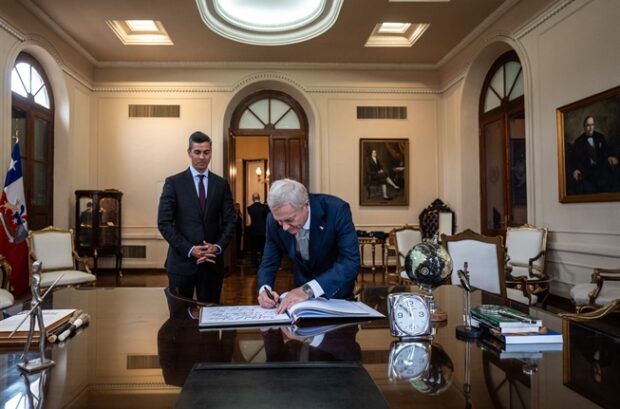 Presidente José Antonio Kast firmando un documento en una mesa.