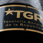 Nuevo revés judicial para la Tesorería: Corte ordena paralizar cobro forzado del CAE en Arica Plano detalle de una placa negra con letras doradas de la Tesorería General de la República y su sigla TGR.