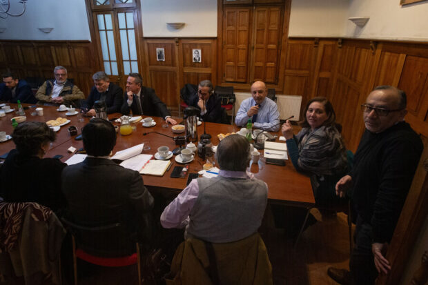 Presidentes y jefes de bancada de los partidos sentados en una mesa con documentos encima.