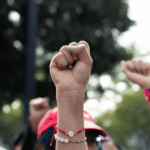 Derechos humanos, más allá del derecho Plano detalle de puños alzados en una marcha.