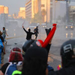 Registro de Vándalos e Incivilidades: el caso británico como modelo derogado por su propio fracaso Manifestantes gesticulan frente a vehículos blindados de la policía lanzando chorros de agua en una avenida urbana.