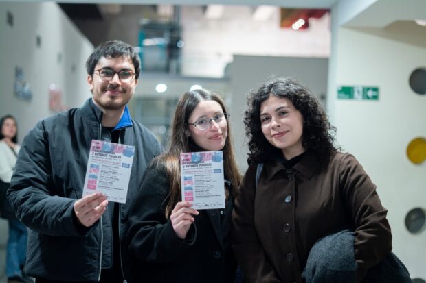 Un hombres y dos mujeres posan para una foto mientras sostienen flyers de “Cine, desobediencia y futuros posibles”. 