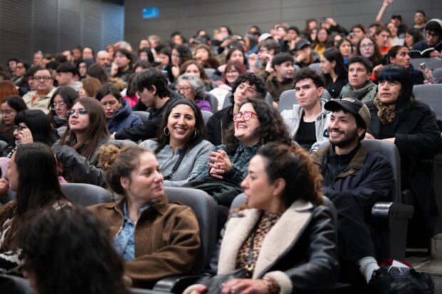 Espectadores en una sala de cine. La luz esta prendida y varios miran al frente sonriendo.