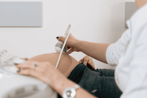 Plano detalle de un obstetra realizando una ecografía a una embarazada.