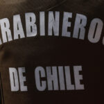 Parte trasera de un chaleco verde de Carabineros, que dice "Carabineros de Chile".