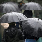 DMC prevé debilitamiento de las lluvias este sábado, pero alerta por nuevo pulso del sistema frontal hacia el norte Personas paseando con paraguas en Santiago.