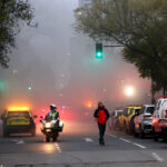 Vehículos de Seguridad Providencia y motorista de Carabineros atendiendo una emergencia en una calle cubierta por densa humareda.