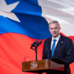 "No siempre aportan": Presidente Kast llama a partidos oficialistas a evitar instalar temas fuera de la agenda del Gobierno Presidente José Antonio Kast da discurso desde un podio y con una bandera de Chile que cubre todo el fondo.