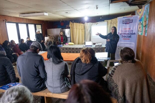 Expositora realiza una presentación frente a dirigentes y vecinos reunidos en una sala.