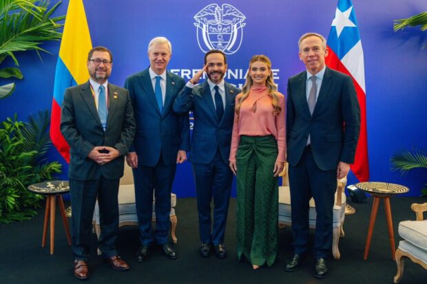 Autoridades chilenas y colombianas posan para una foto protocolar con banderas de Chile y Colombia detrás.