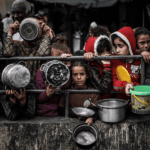 “Anatomía de un genocidio”: exposición fotográfica sobre Palestina llega al Teatro Municipal de Viña del Mar Personas amontonadas levantan ollas vacías en un intento por conseguir comida.