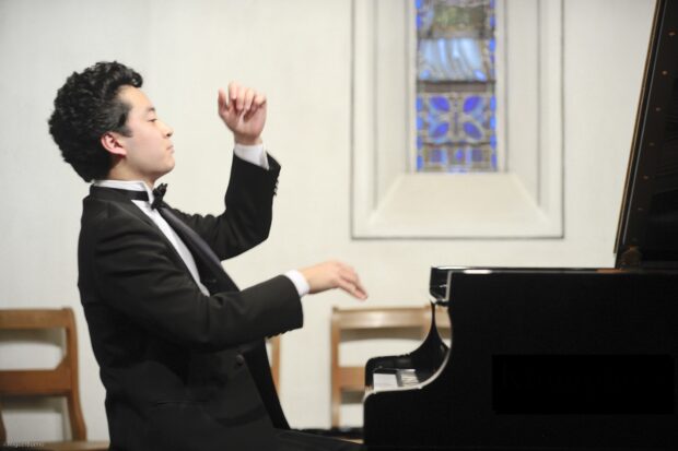 Foto de perfil del pianista japonés, Ryutaro Suzuki, tocando el piano.