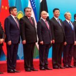 Cumbre de la OCS: China y Rusia buscan cerrar filas ante la escalada de EE.UU. contra Irán Ocho líderes mundiales posan para una foto uno al lado del otro sobre una alfombra roja. Detrás de ellos las banderas de sus países.