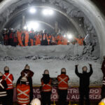 Extensión Línea 6: Metro concreta encuentro de túneles y proyecta llegada a Lo Errázuriz para 2028 Grupo de trabajadores e ingenieros con cascos blancos y chalecos reflejantes presencian el encuentro de dos frente de excavación en un túnel de metro.