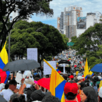 De la Espriella enfrenta su primera protesta con decenas de miles de manifestantes Decenas de manifestantes en una calle urbana rodeada por árboles y edificios.