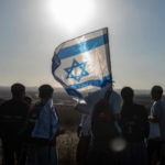 Comisión de la ONU acusa a Israel de "exterminio" en Cisjordania y mantiene acusación de "genocidio" en Gaza Bandera de Israel alzada a contraluz por un grupo de israelíes.